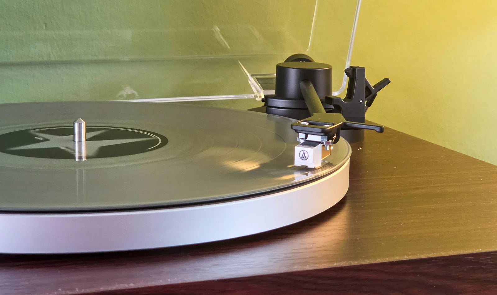 Groene vinylplaat draait op de Aulo, met de toonarm en het Audio-Technica-element van dichtbij, review door Bright