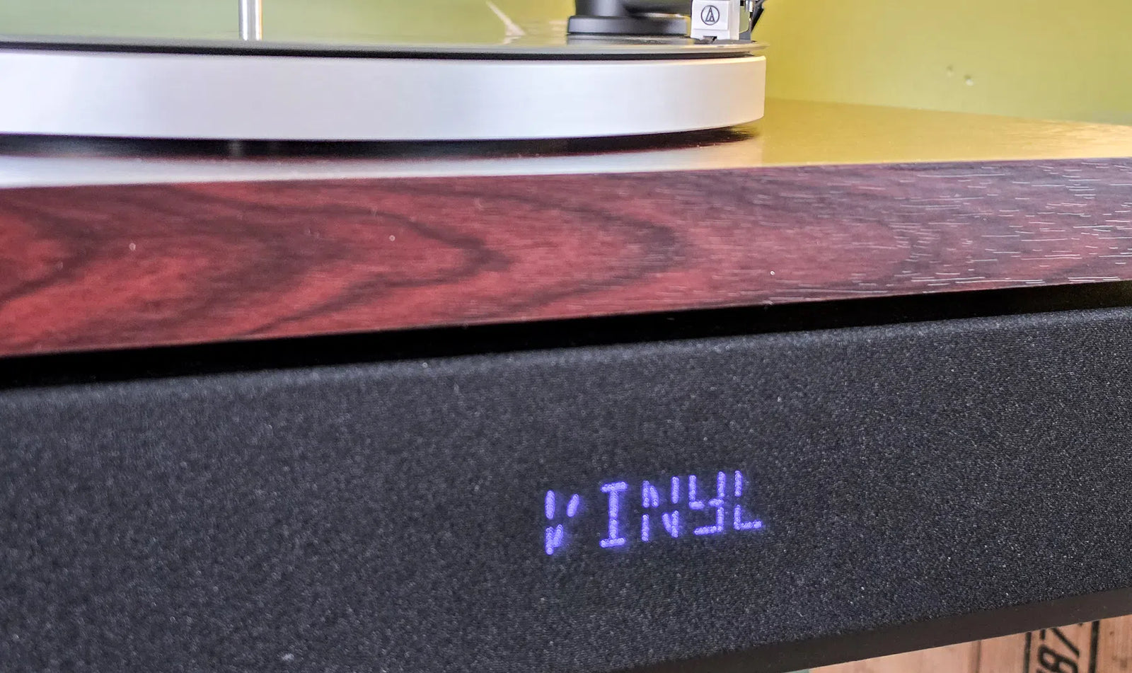 De houten bovenkant van de Aulo rust op de zwarte geluidsset met oplichtend VINYL-display, review door Bright