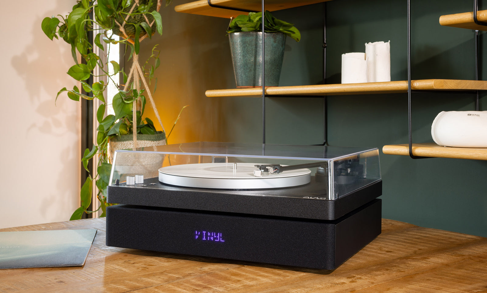 Aulo platenspeler in het zwart met gesloten stofkap, rustig opgesteld in een warm interieur met planten, review door FWD