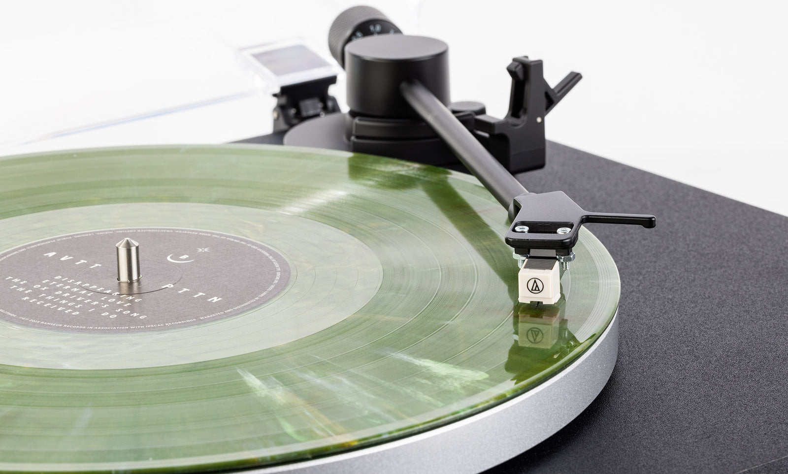 Groene vinylplaat draait op de Aulo, met de toonarm en het element van dichtbij