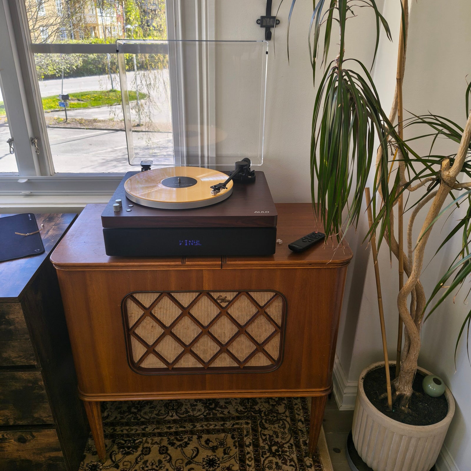 Aulo platenspeler in tegenlicht bij het raam met oplichtend VINYL-display en zichtbaar speakerfront
