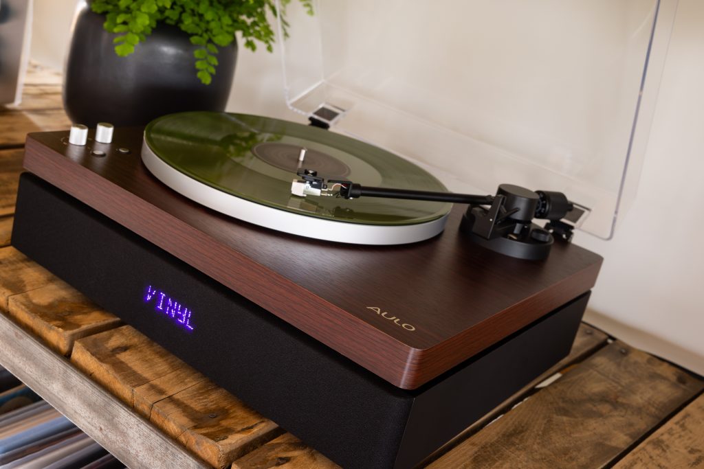 Aulo platenspeler in Dark Wood met groene vinylplaat op een houten meubel
